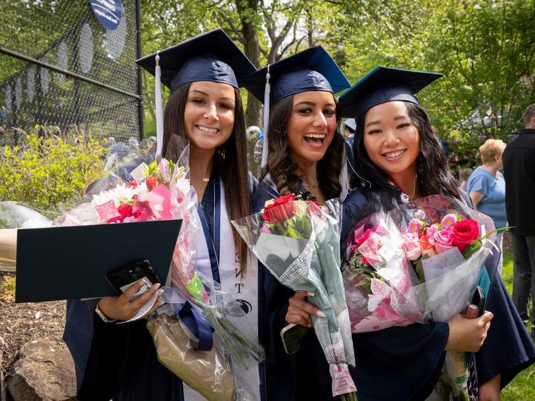 Three students smiling after commencement